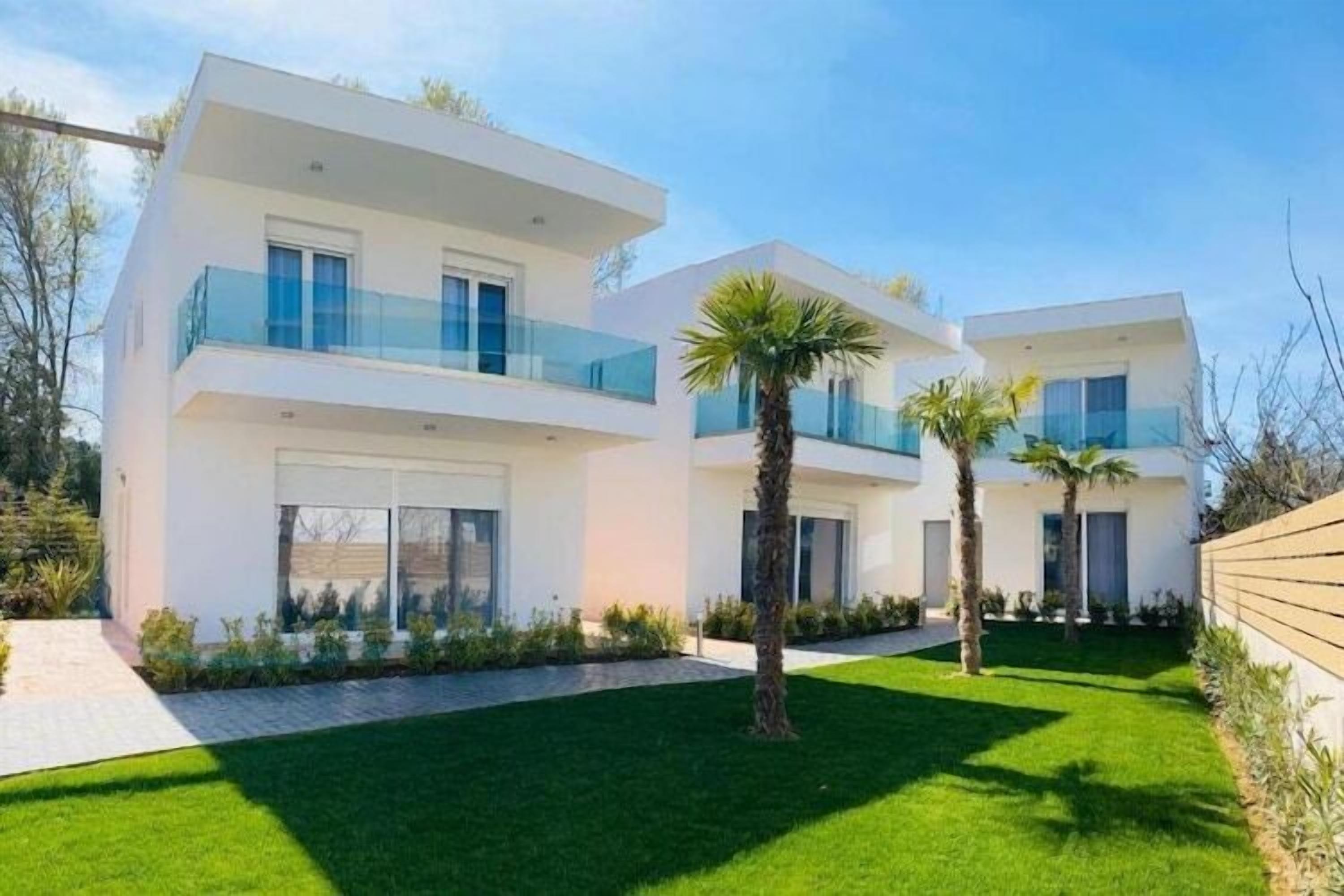Une maison moderne à deux étages, dotée d’un toit plat, de grandes fenêtres et d’un balcon.