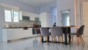 A modern kitchen with white cabinets, a marble countertop, and a dining area with four chairs. - Villas Acrotel Porto Brava, Ormos Panagias (Ormos Panagias)
