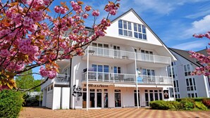 A two-story building with a balcony, a sign reading "MODE EXPRESS," and a clear blue sky. - Fewo mit Balkon und Strandkorb am Strand (Baabe)