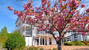A building with a sign reading "Motel Express" and a tree with pink blossoms in front. - Fewo mit Balkon und Strandkorb am Strand (Baabe)