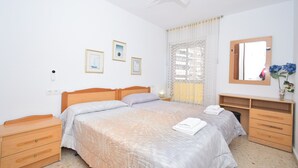 A bedroom with a bed, bedside tables, a dresser, a ceiling fan, and a window with curtains. - LAS ADELFAS (2 BEDROOM) (Benidorm)