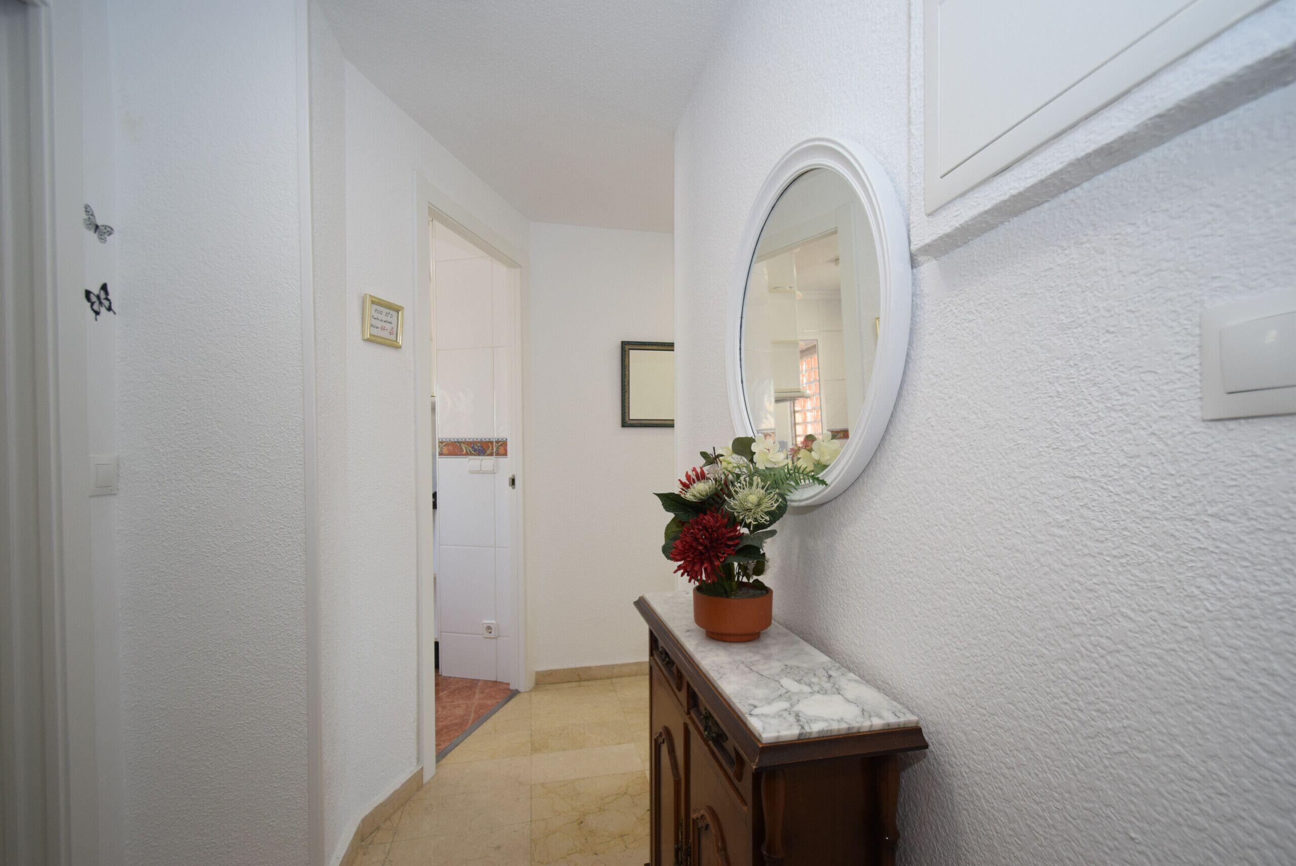 A hallway with a marble-topped dresser, a mirror, and a potted plant.