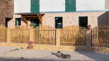 A building with a wooden fence, a dog lying on the ground, and potted plants.