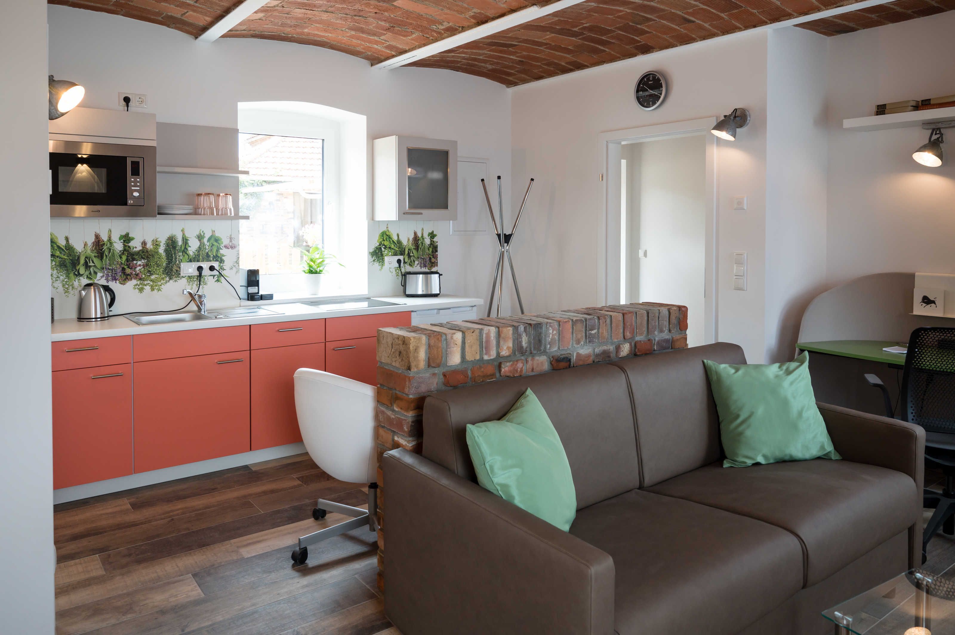 A modern kitchen with a microwave, cabinets, and a brick accent wall.