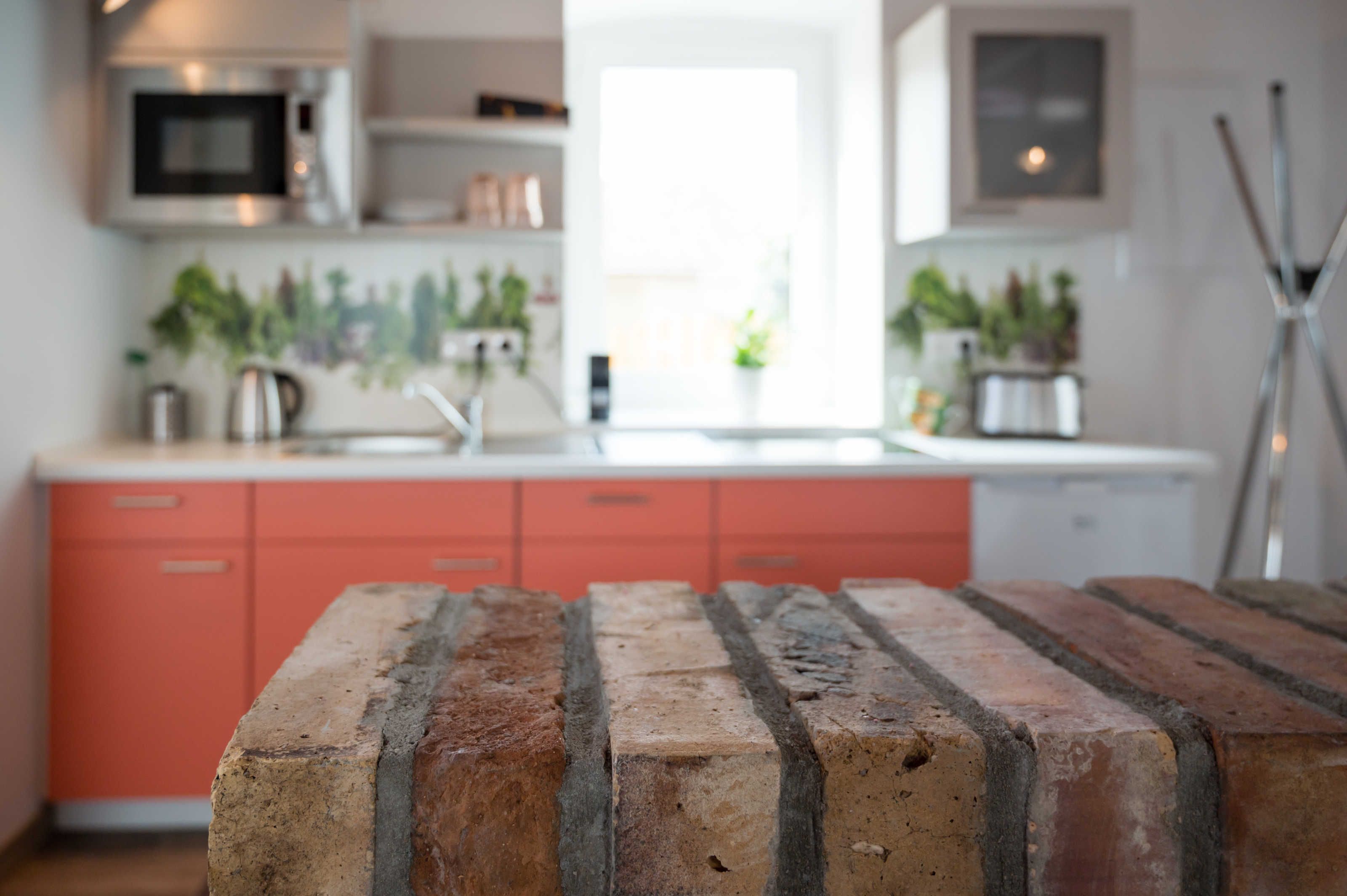 A kitchen with a brick countertop, red cabinets, and a microwave.