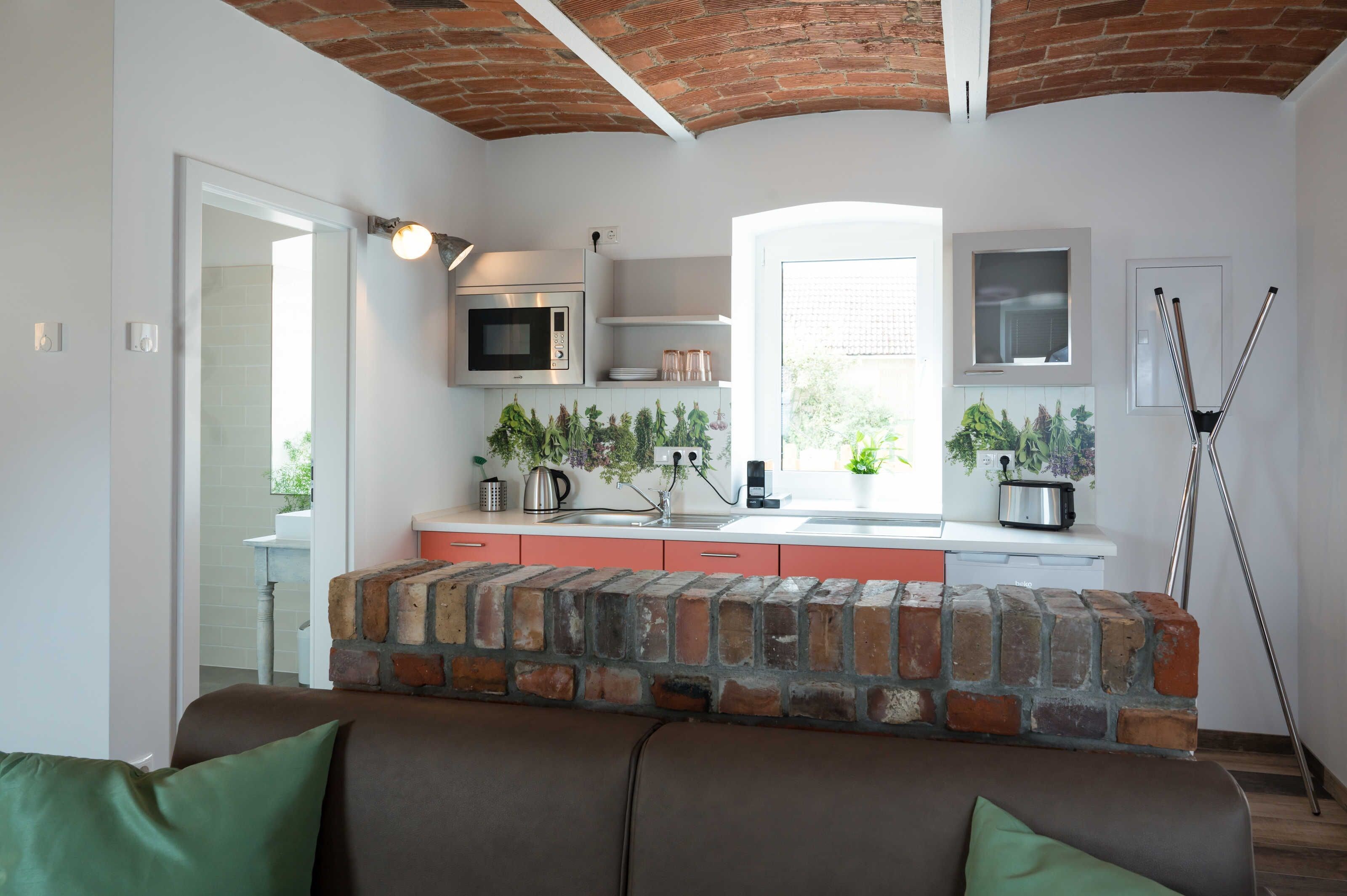 A kitchen with a brick accent wall, a microwave, a kettle, and a toaster.