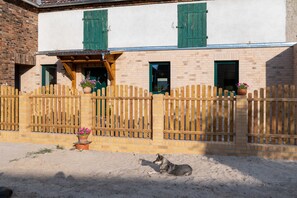 Een gebouw met een houten omheining, een hond die op de grond ligt, en potplanten.