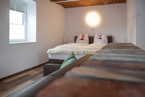 Een slaapkamer met een bed, nachtkastje, raam en een wandlamp.