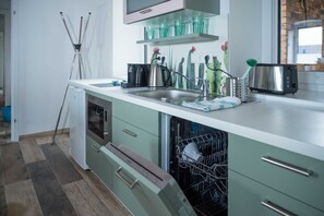Een moderne keuken met een vaatwasser, een spoelbak, een broodrooster en decoratief glaswerk op het aanrecht.