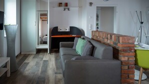 A modern living room with a grey sofa, a brick accent wall, a desk, and a large grey vase.