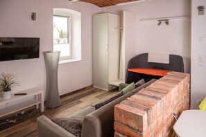 Een moderne woonkamer met een flatscreen televisie, een hoge vloerlamp, een open haard van baksteen en een bank.
