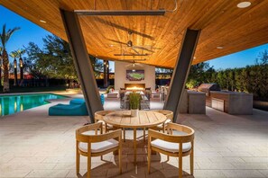 An outdoor patio with a pool, wooden furniture, and a TV screen. - Live the High Life - Lavish Scottsdale Home (Scottsdale)