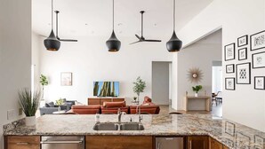 A modern kitchen with a granite countertop, stainless steel appliances, and pendant lighting.