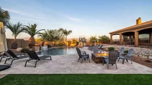 A poolside area with lounge chairs, a fire pit, and a waterfall feature. - Dreamy Desert Oasis with Game Room, Heated* Pool! (Scottsdale)