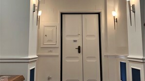 Un couloir doté d’une double porte, de deux appliques murales et d’une table en bois.
