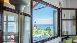 Une pièce dotée d’une grande fenêtre donnant sur un balcon avec vue sur la mer.