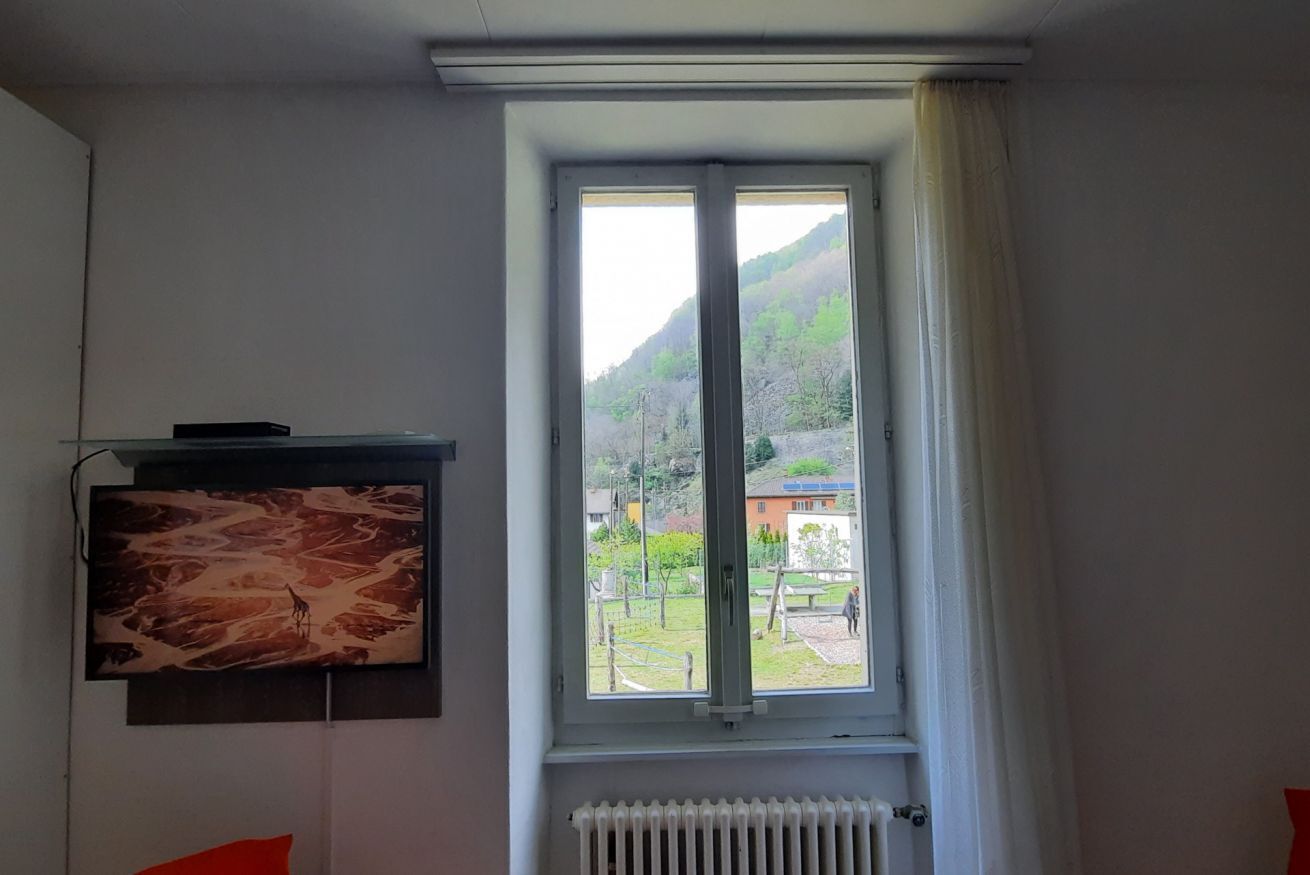 A room with a large window, a radiator below it, and a framed picture on the wall.