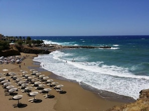 Ein Strand mit Sonnenliegen und einer steinernen Mole.