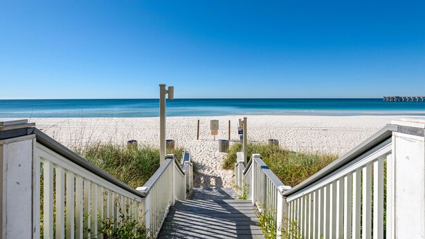 A wooden staircase leading to a beach with a clear blue sky.