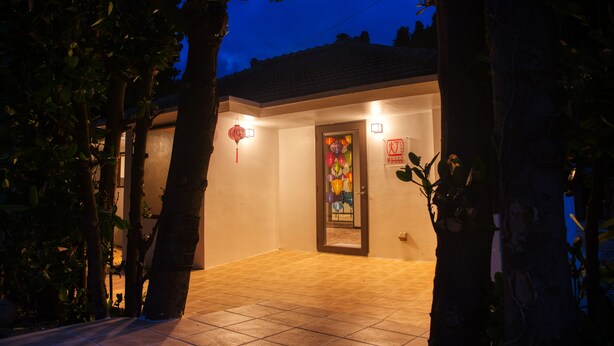 A house with a tiled entrance, a door with a colorful glass panel, and a red lantern on the wall. - ADAN RESORT Lamp (Motobu)
