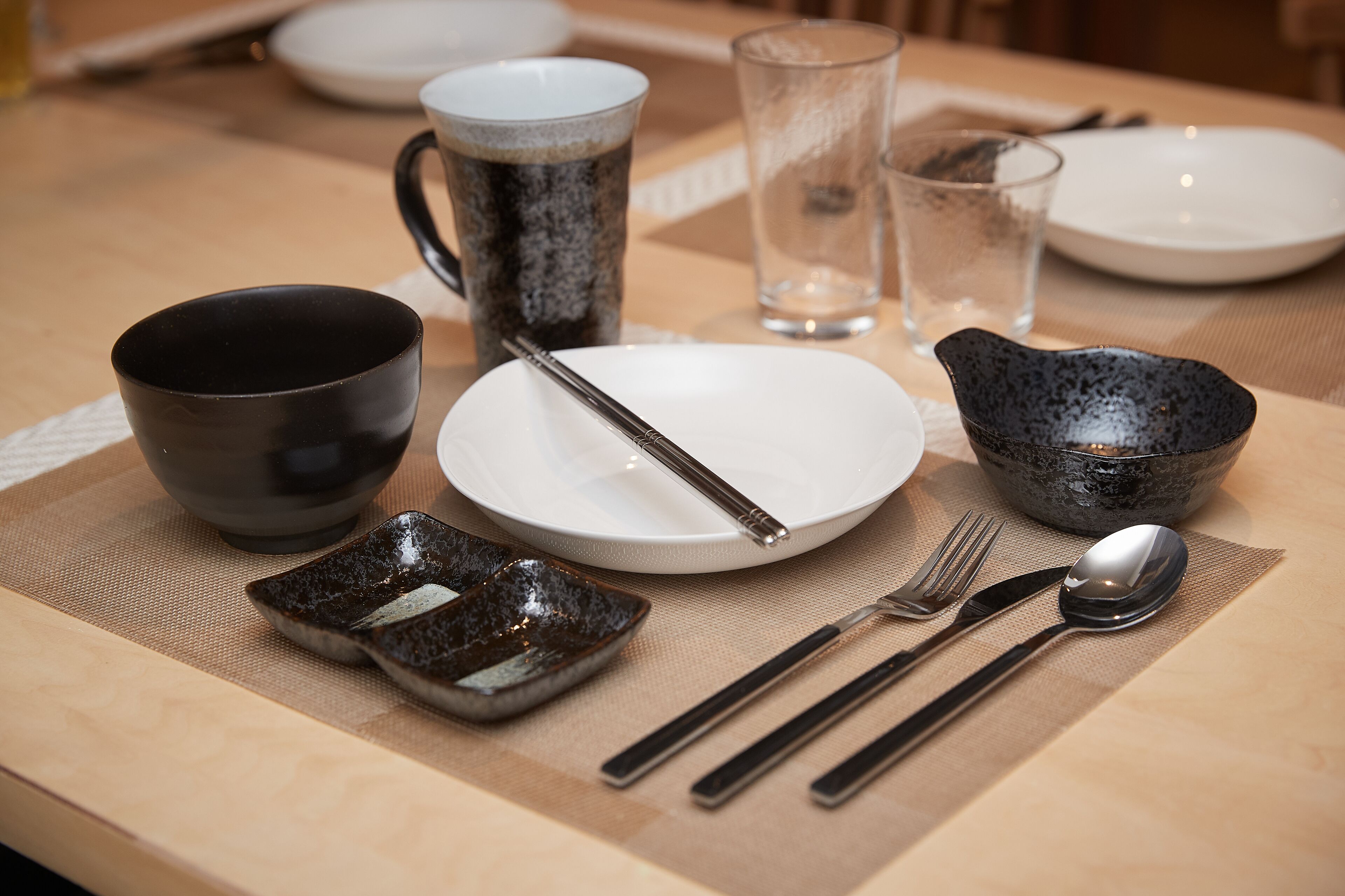 A dining table set with plates, bowls, a cup, and cutlery.