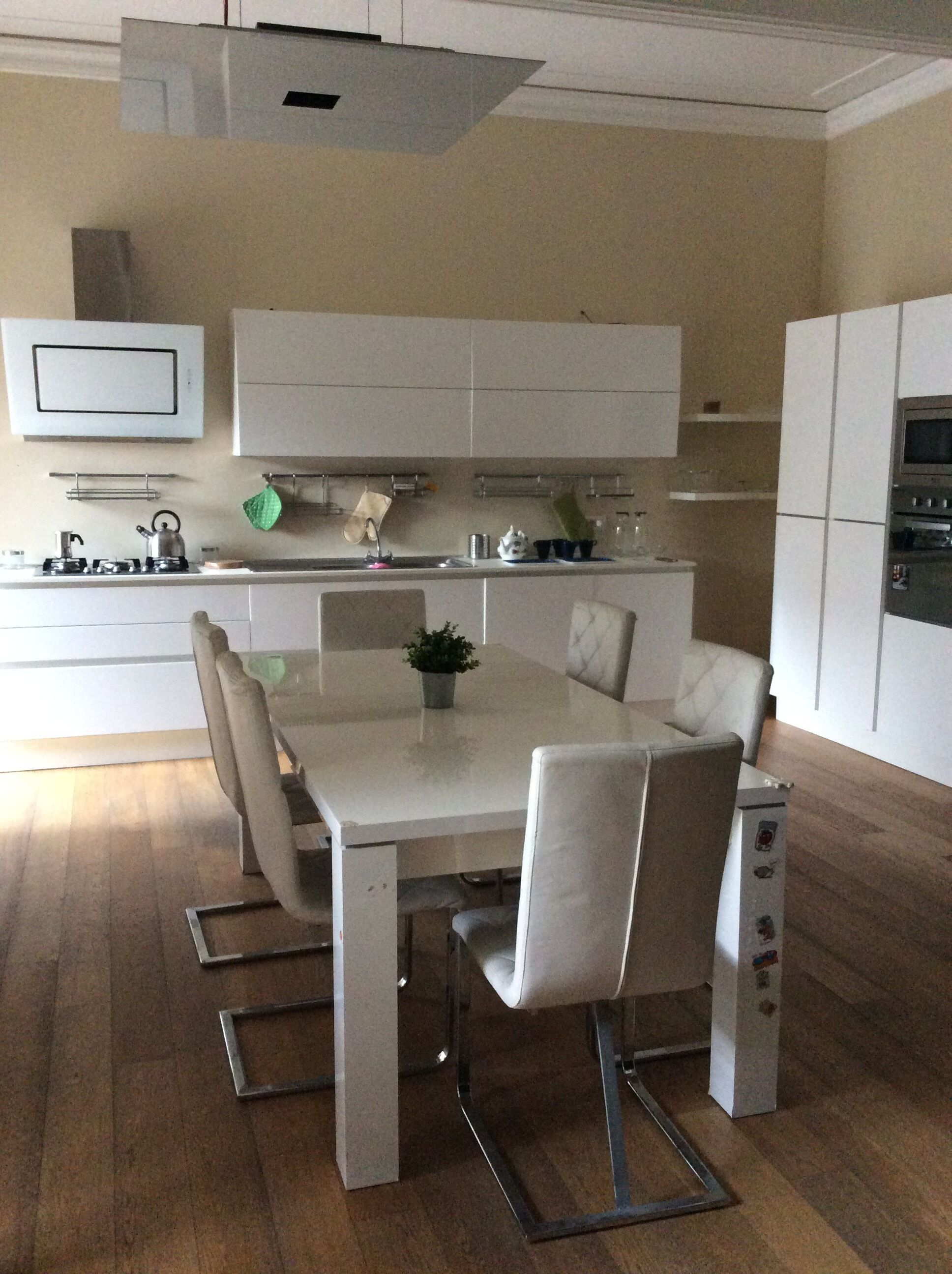 Eine moderne Küche mit weißen Schränken, einem Esstisch mit Stühlen und einem eingebauten Backofen.