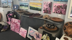 Una galería con diversas obras de arte y cerámica exhibidas en estantes y mesas.