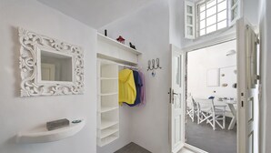 Un baño con tocador blanco, un espejo con marco decorativo, un toallero con toallas y una zona de ducha visible a través de una puerta abierta.