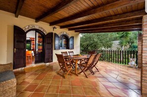 Relax in this serene outdoor space with a dining table, wicker sofa, and comfortable seating.