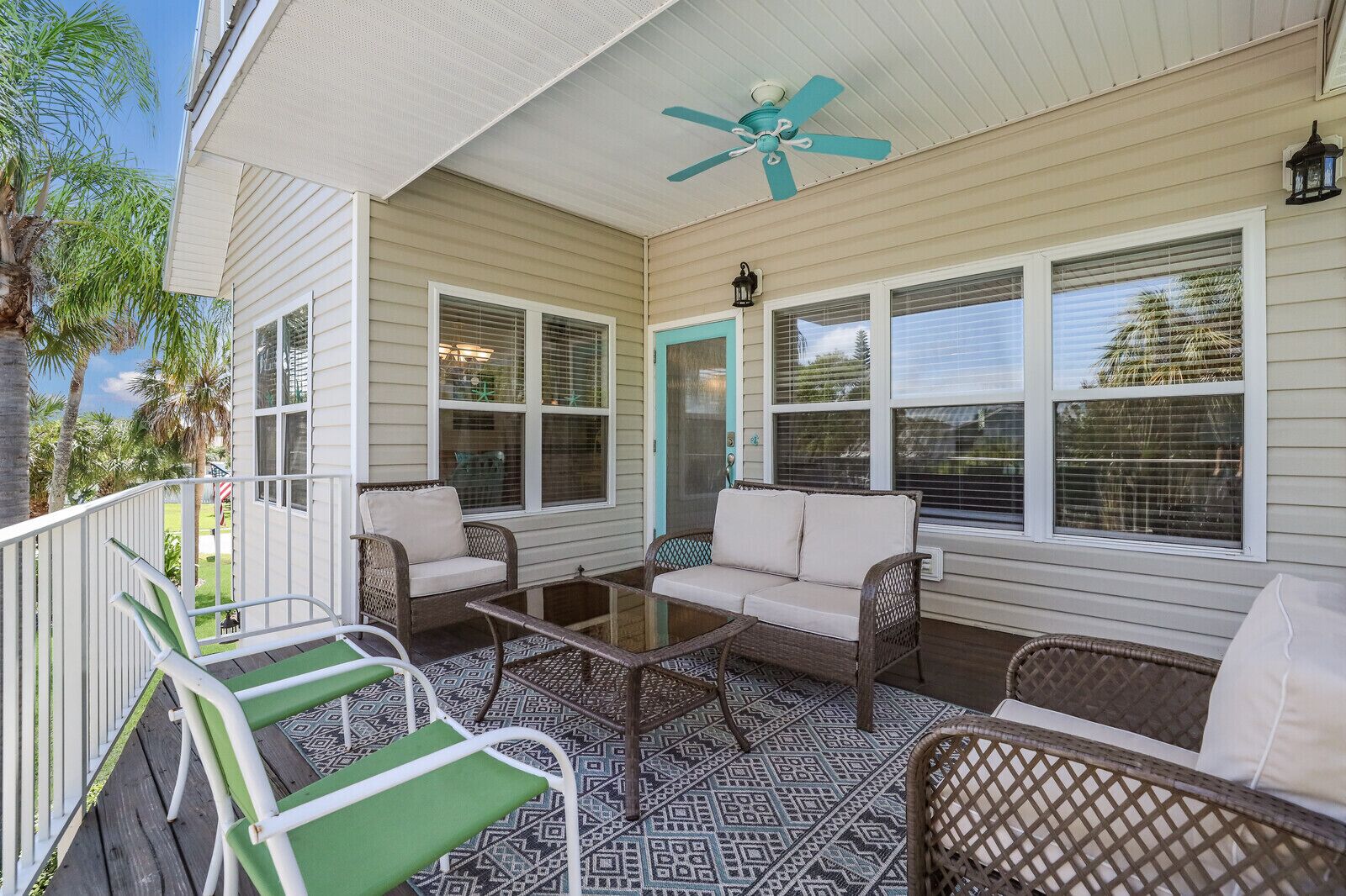 A covered porch with wicker furniture, a ceiling fan, and a view of the outdoors.