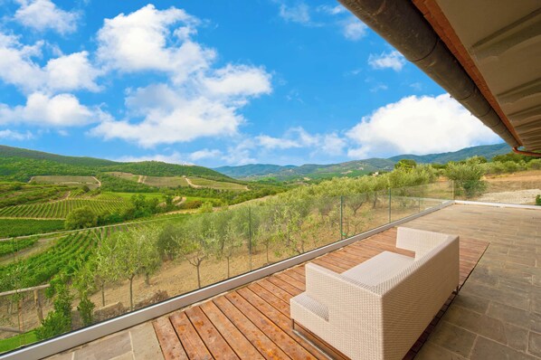 A balcony with a view of a vineyard and distant hills. - AMORE RENTALS - Villa Bacci with Indoor Heated Pool, Garden and Parking (Toscana)