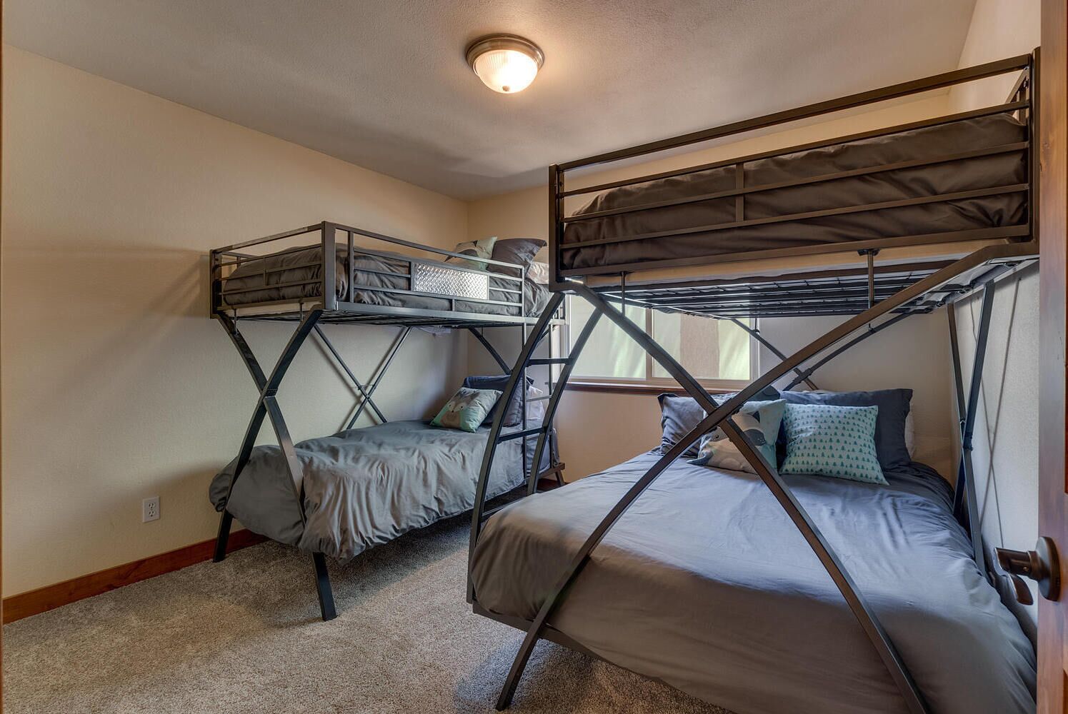 Une chambre de dortoir avec des lits superposés, un sol recouvert de moquette et un luminaire au plafond.