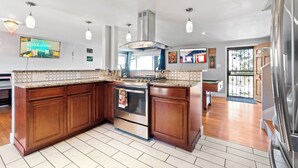 Een moderne keuken met een groot schiereiland, roestvrijstalen apparatuur en hanglampen.
