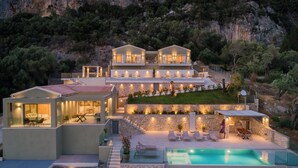 A modern villa with a pool, outdoor seating, and a view of the surrounding cliffs.