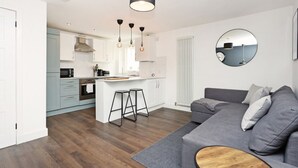 Een moderne keuken met witte kastjes, een centraal eiland met krukken en hangende verlichting.