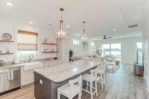 A modern kitchen with a large island, white cabinetry, and pendant lighting. - Fin & Tonic! Luxurious River View Home with Rooftop Deck (Folly Beach)