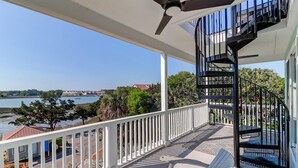 Ein Balkon mit Blick auf einen Fluss, ein Deckenventilator und eine Wendeltreppe.