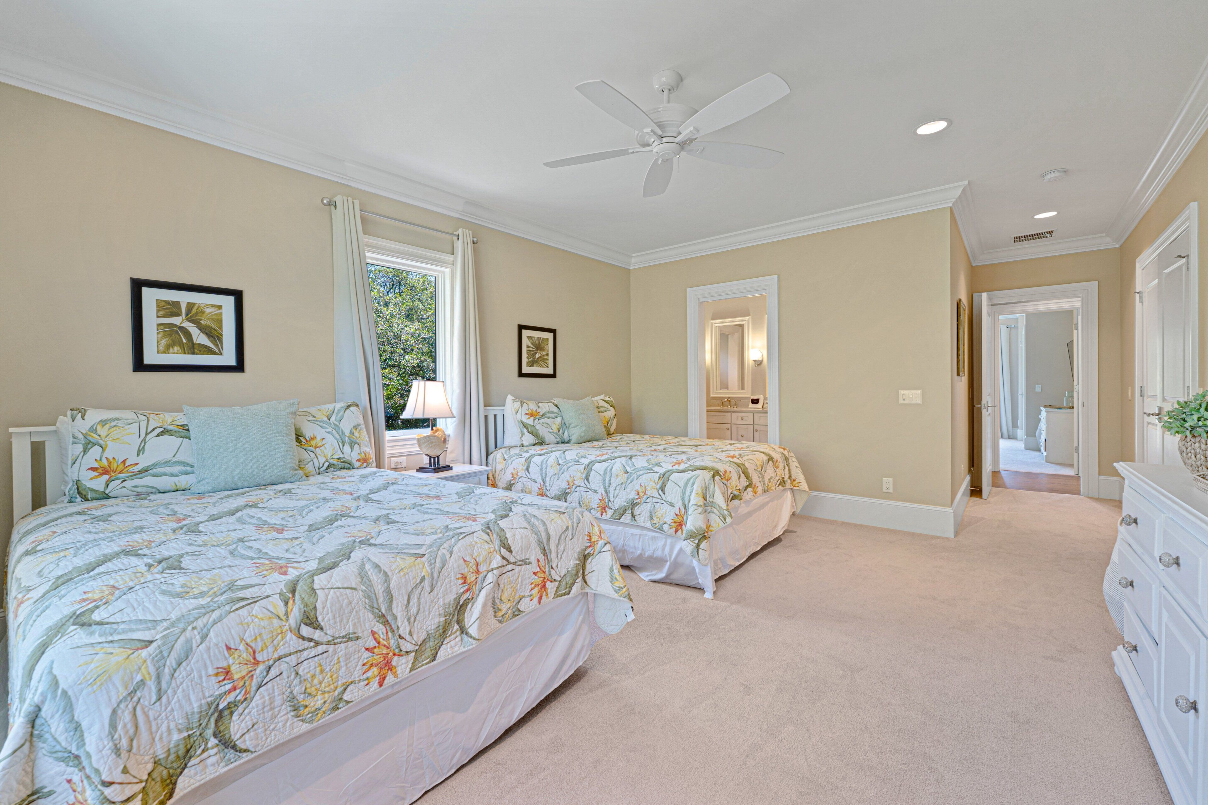 A bedroom with two beds, a ceiling fan, and a view of the outdoors.