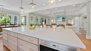 A spacious kitchen with a large island, pendant lighting, and a view of the outdoors.