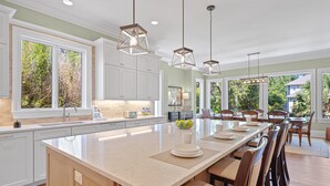 A spacious kitchen with a large island, white cabinetry, and pendant lighting.