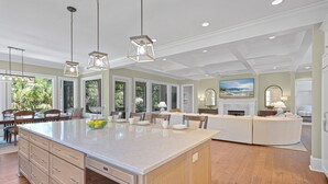 A spacious kitchen with a large island, wooden cabinets, and pendant lighting.