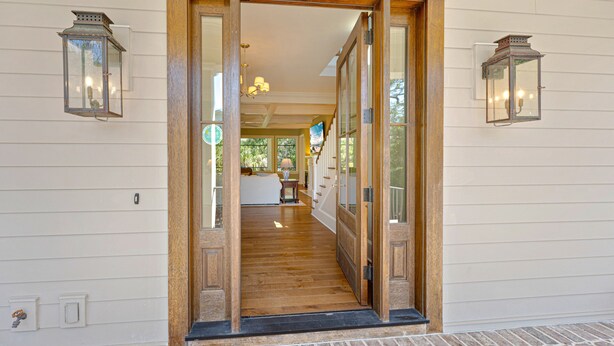 A wooden door leading into a room with a fireplace, a television, and a window.