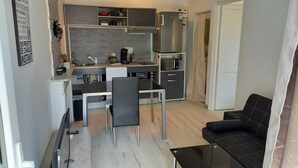 Une cuisine compacte comprenant un coin repas, un réfrigérateur et un canapé.