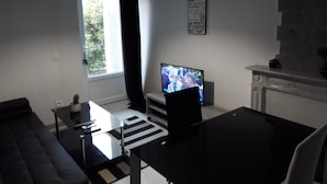 Un salon avec un canapé, une table basse, un téléviseur et une cheminée.