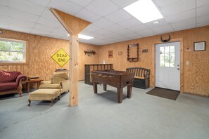 A room with a foosball table, a sofa, a chair, and a wooden wall with a 'DEAD END' sign.