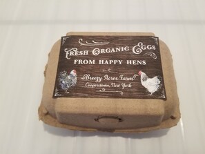 A package labeled "Fresh Organic Eggs from Happy Hens" with a rooster illustration and location details. - Breezy Acres Farm Apt 1- large yard, fire pit, game room near Cooperstown (Cooperstown)