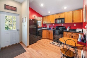 A kitchen with wooden cabinets, a black refrigerator, a microwave, and a stove. - Breezy Acres Farm Apt 1- large yard, fire pit, game room near Cooperstown (Cooperstown)