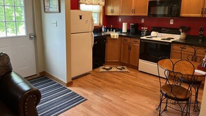 Una cocina compacta con armarios de madera, un refrigerador, un microondas, una estufa y un lavamanos.