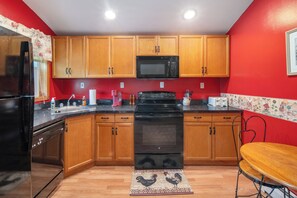 Una cocina con armarios de madera, un microondas negro, una estufa y un fregadero.