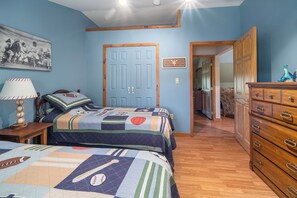A bedroom with a bed, a dresser, a lamp, and a door.